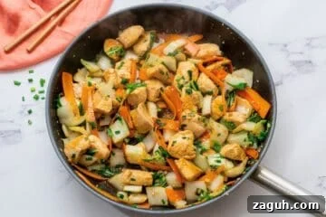 Chicken, bok choy, carrots, and a soy honey sauce tossed together in skillet.