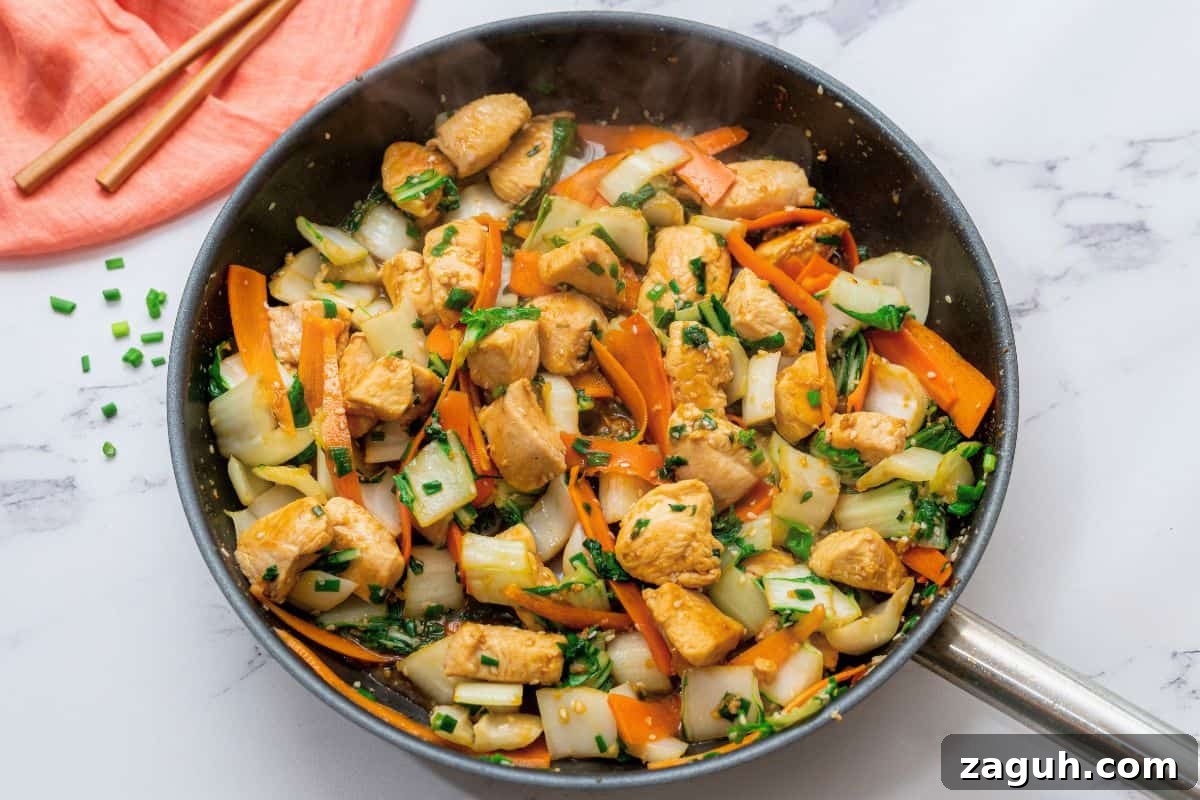 Chicken, bok choy, carrots, and a soy honey sauce tossed together in skillet.