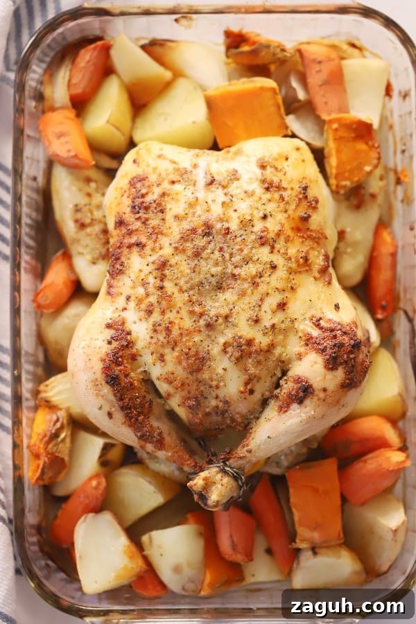 A baking dish with a whole chicken surrounded by cut up potatoes and carrots ready to make this roasted chicken and potatoes recipe.