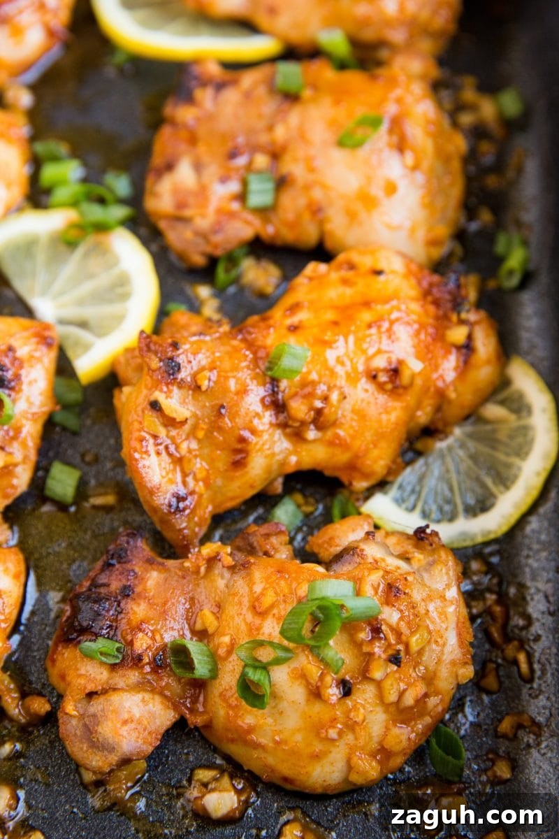 Crispy Lemon Garlic Baked Chicken Thighs with Herb Pan Sauce 2 Casserole dish with baked boneless lemon garlic chicken thighs with sliced lemon and green onion.