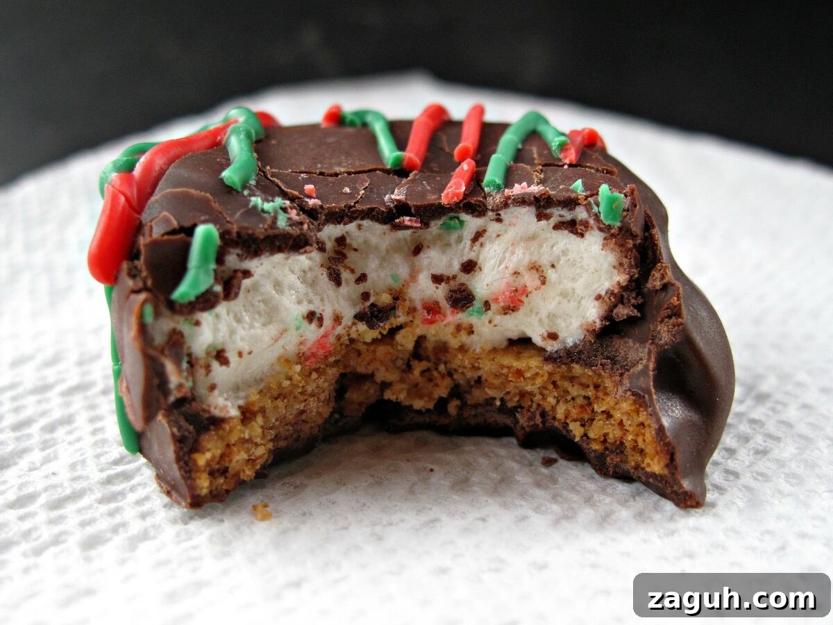 Chocolate Marshmallow (Mallomar) Cookies- This cookie is the first to be grabbed on holiday platters! A graham cracker base topped with a marshmallow and coated in chocolate. Drizzle with colors to match your holiday! | The Monday Box Cookie with a bite showing inside marshmallow topped graham.