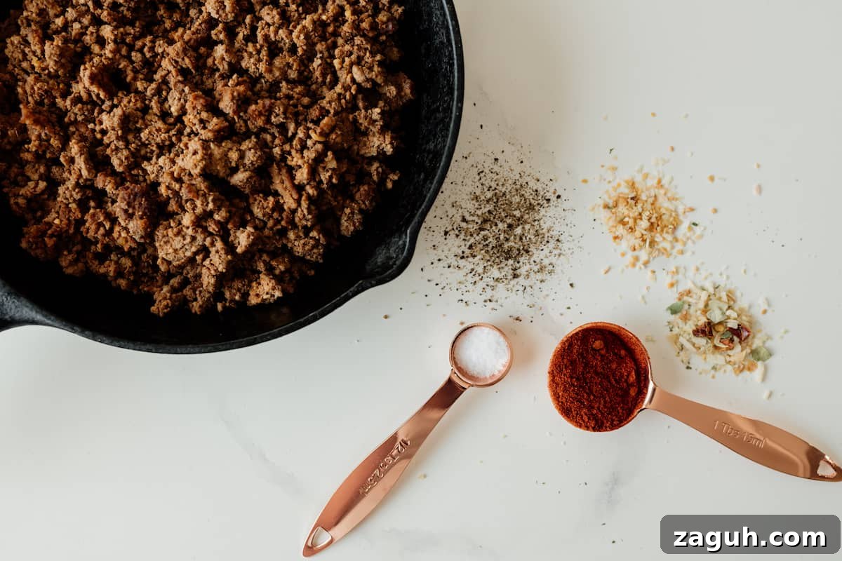 ground beef bison in skillet and spices seasonings on the side