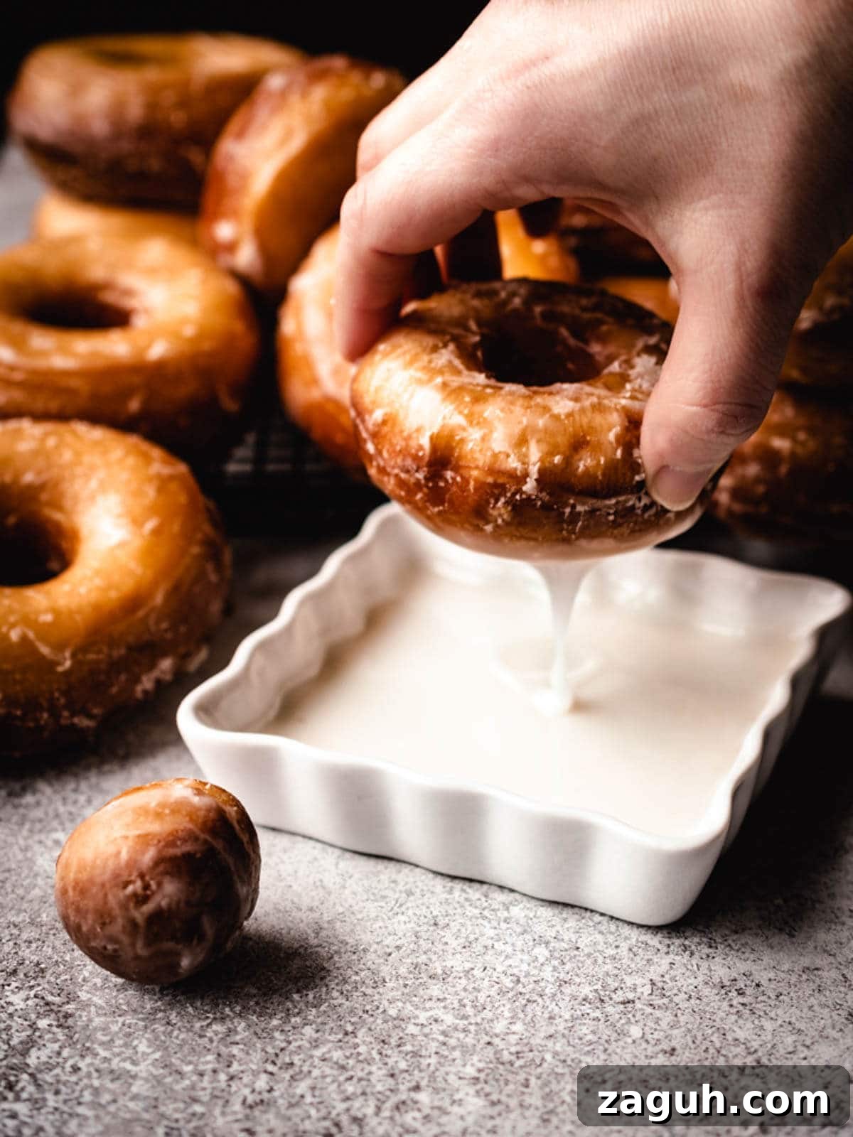 Classic Glazed Donuts: Soft, Shiny, Homemade Recipe 5 Dipping homemade yeast donuts in donut glaze.