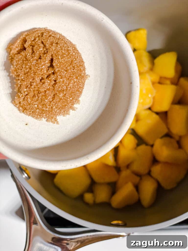 3-Ingredient Mango Compote (Simple Coulis Recipe) 5 process shot showing brown sugar being added to pot of mangos