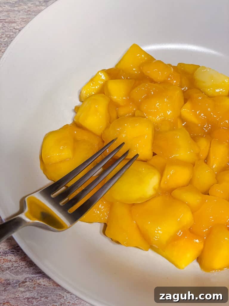 3-Ingredient Mango Compote (Simple Coulis Recipe) 8 process shot of hand mashing mangos in pot