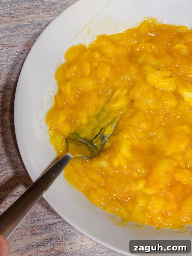 3-Ingredient Mango Compote (Simple Coulis Recipe) 9 process shot of hand mashing mangos in pot