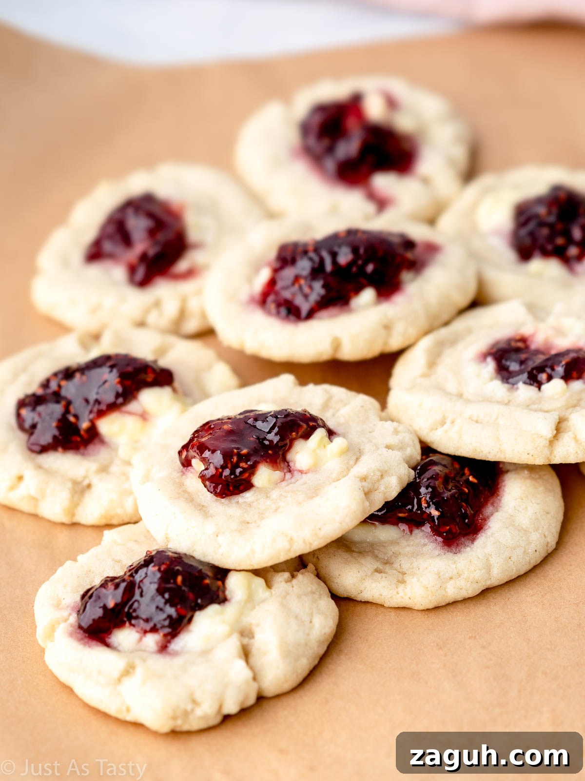 Soft Gluten-Free Raspberry Thumbprint Cookies 2 Pile of raspberry thumbprint cookies on parchment paper.