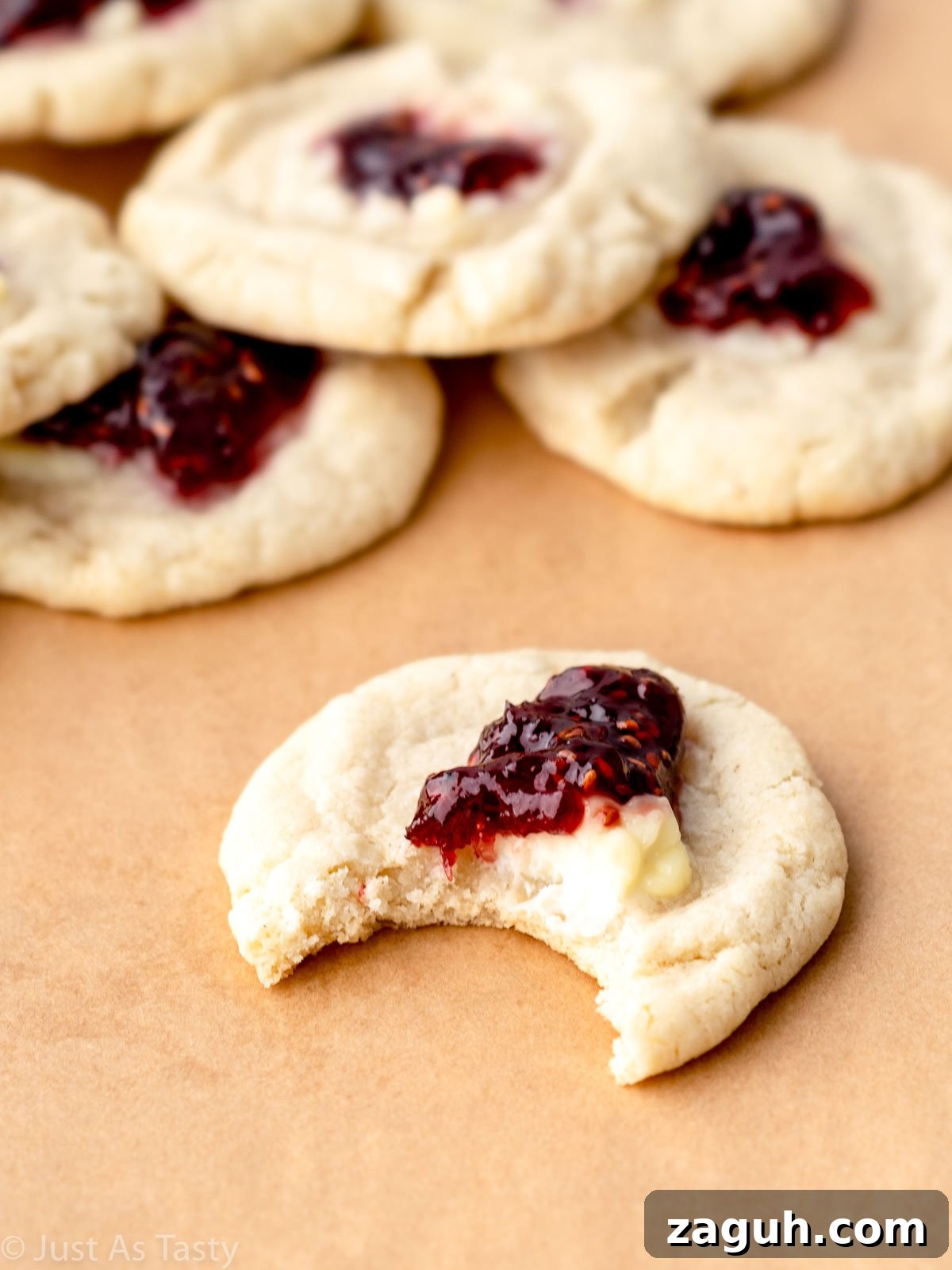 Soft Gluten-Free Raspberry Thumbprint Cookies 3 Raspberry thumbprint cookie with a bite taken out of it.