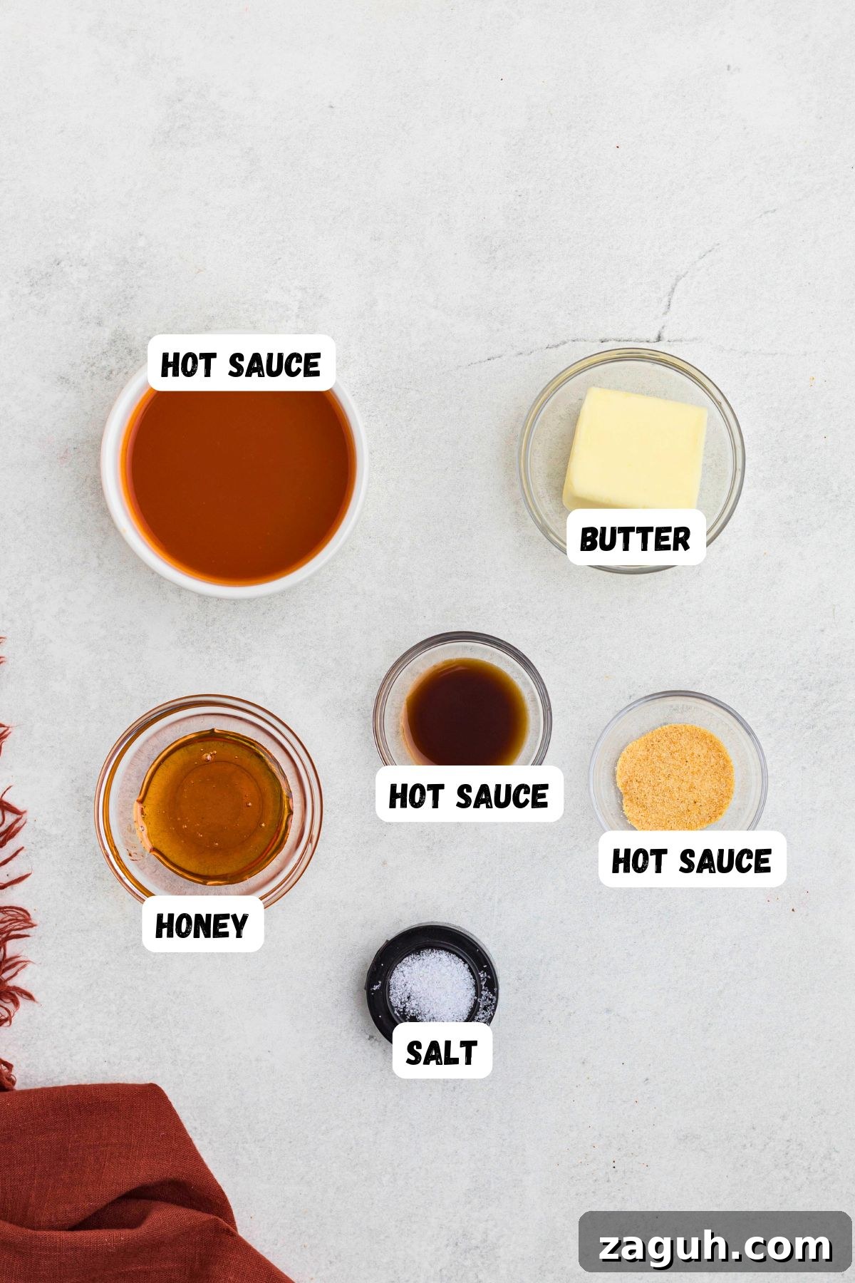 Classic Buffalo Sauce Recipe: Spicy Wing & Dip Sauce in Minutes 3 Ingredients needed to make buffalo sauce, measured into small bowls, on a white marble table.