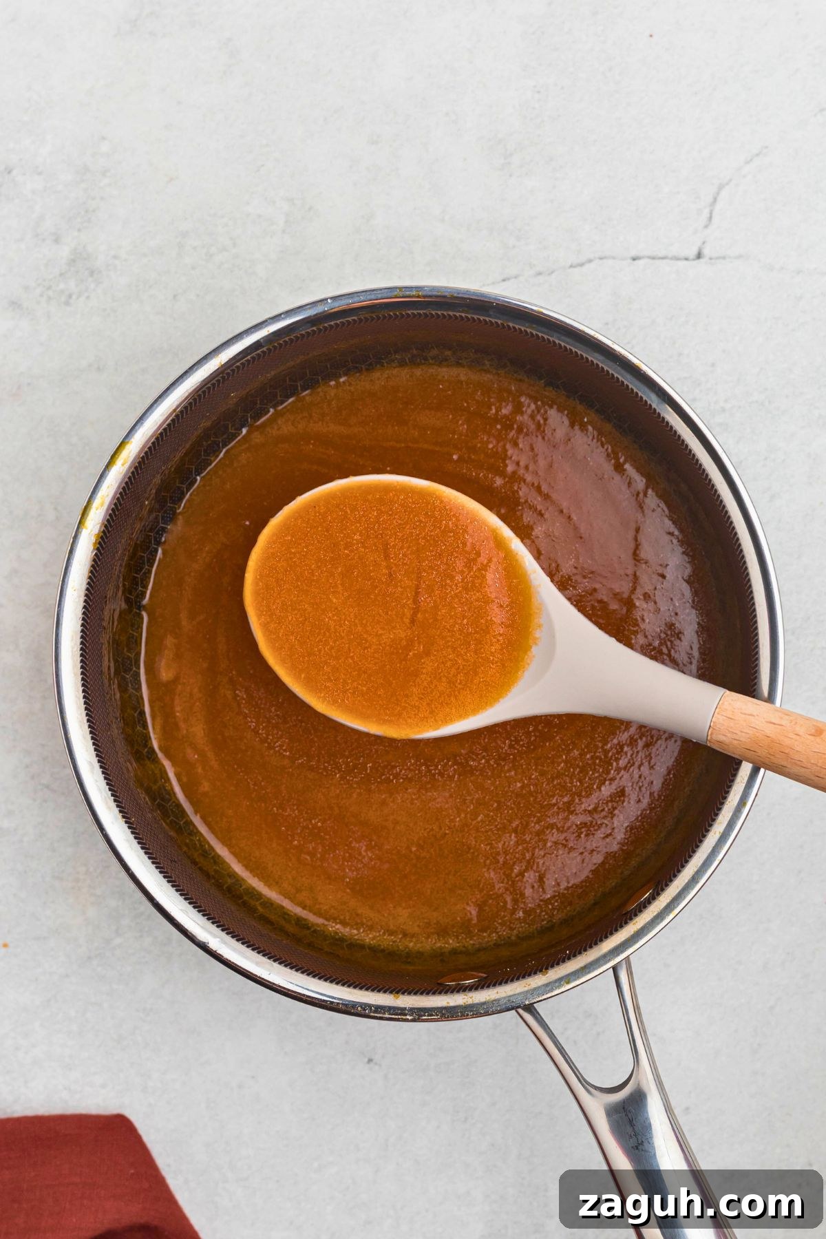 Classic Buffalo Sauce Recipe: Spicy Wing & Dip Sauce in Minutes 6 Creamy and buttery sauce in a saucepan, thickening after it's cooled, being spooned up with a serving spoon.