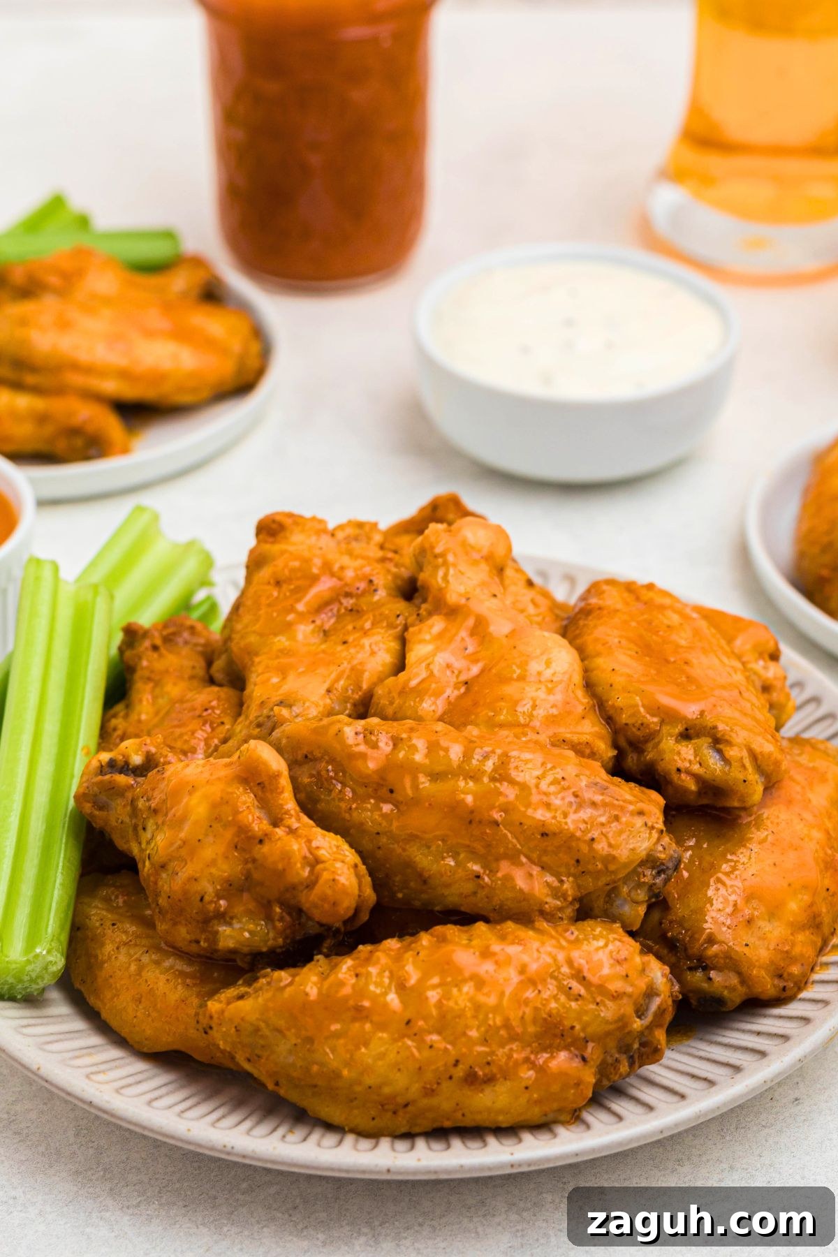 Classic Buffalo Sauce Recipe: Spicy Wing & Dip Sauce in Minutes 8 Crispy baked chicken wings, tossed in buffalo sauce, on a white plate with celery sticks on the plate.