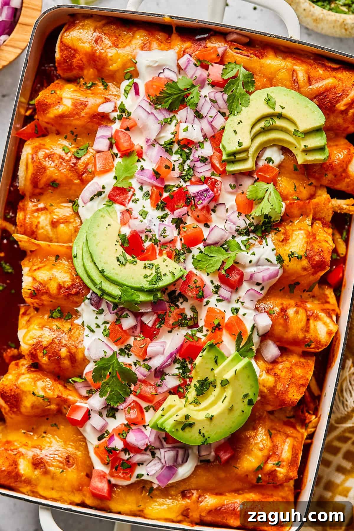 Chicken and black bean enchiladas with toppings in a casserole dish