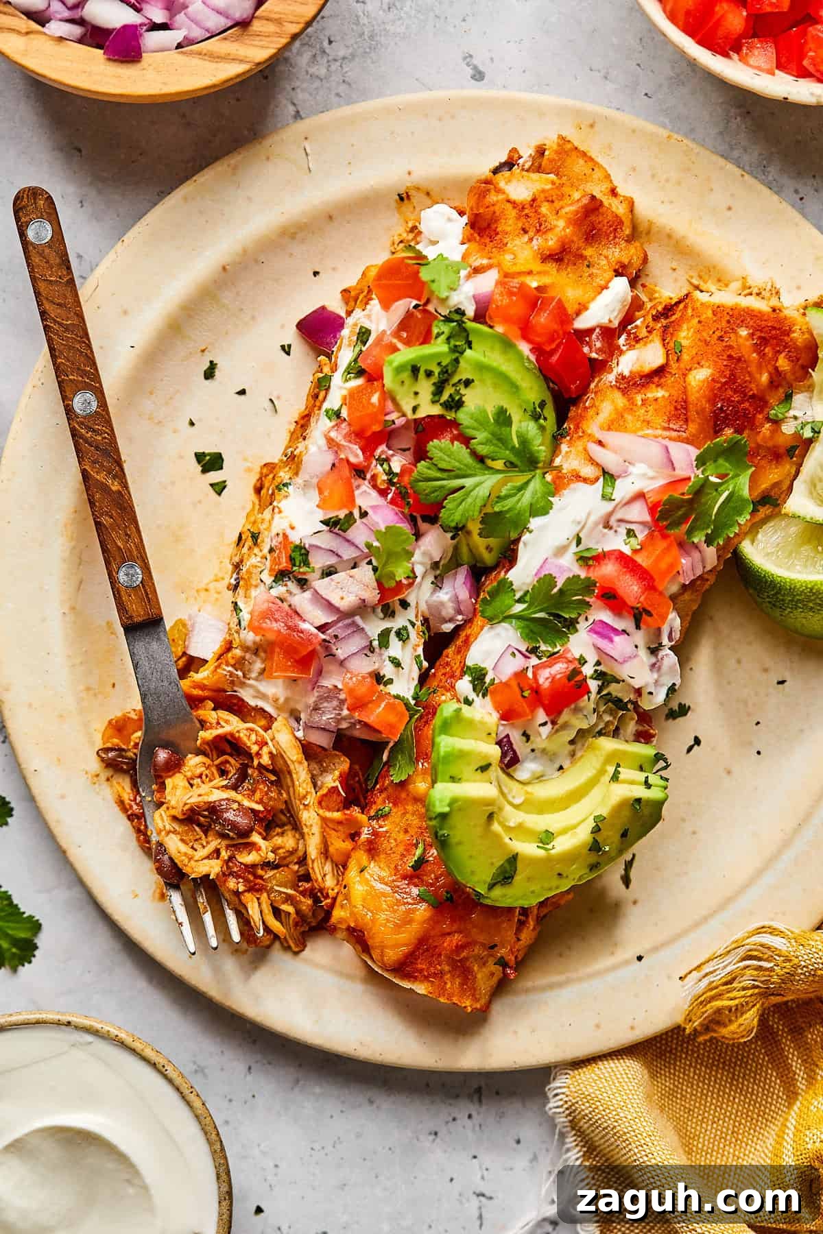 enchiladas on a plate topped with avocado and salsa with a fork resting on the side. 