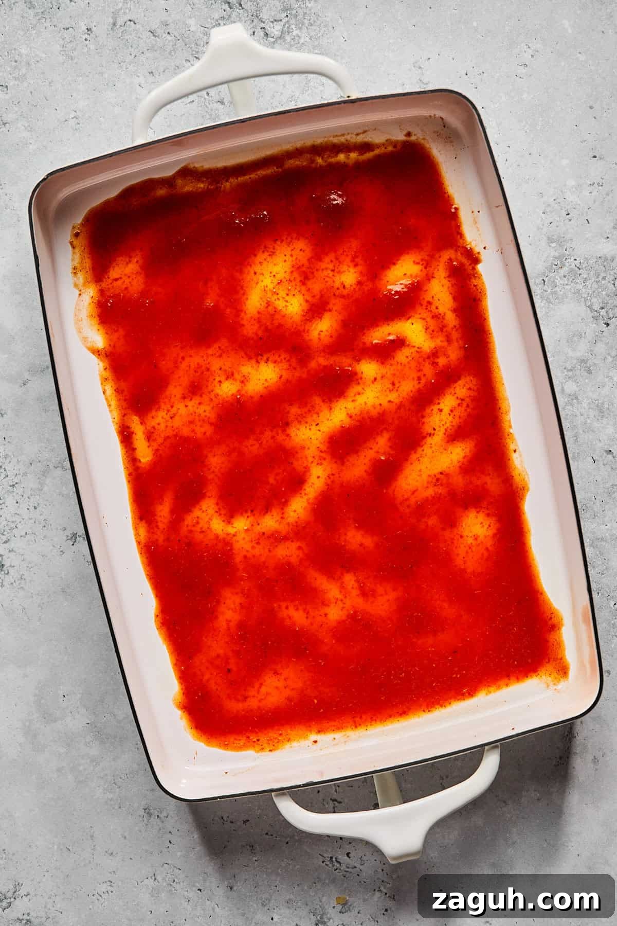 enchilada sauce at the bottom of a casserole dish 