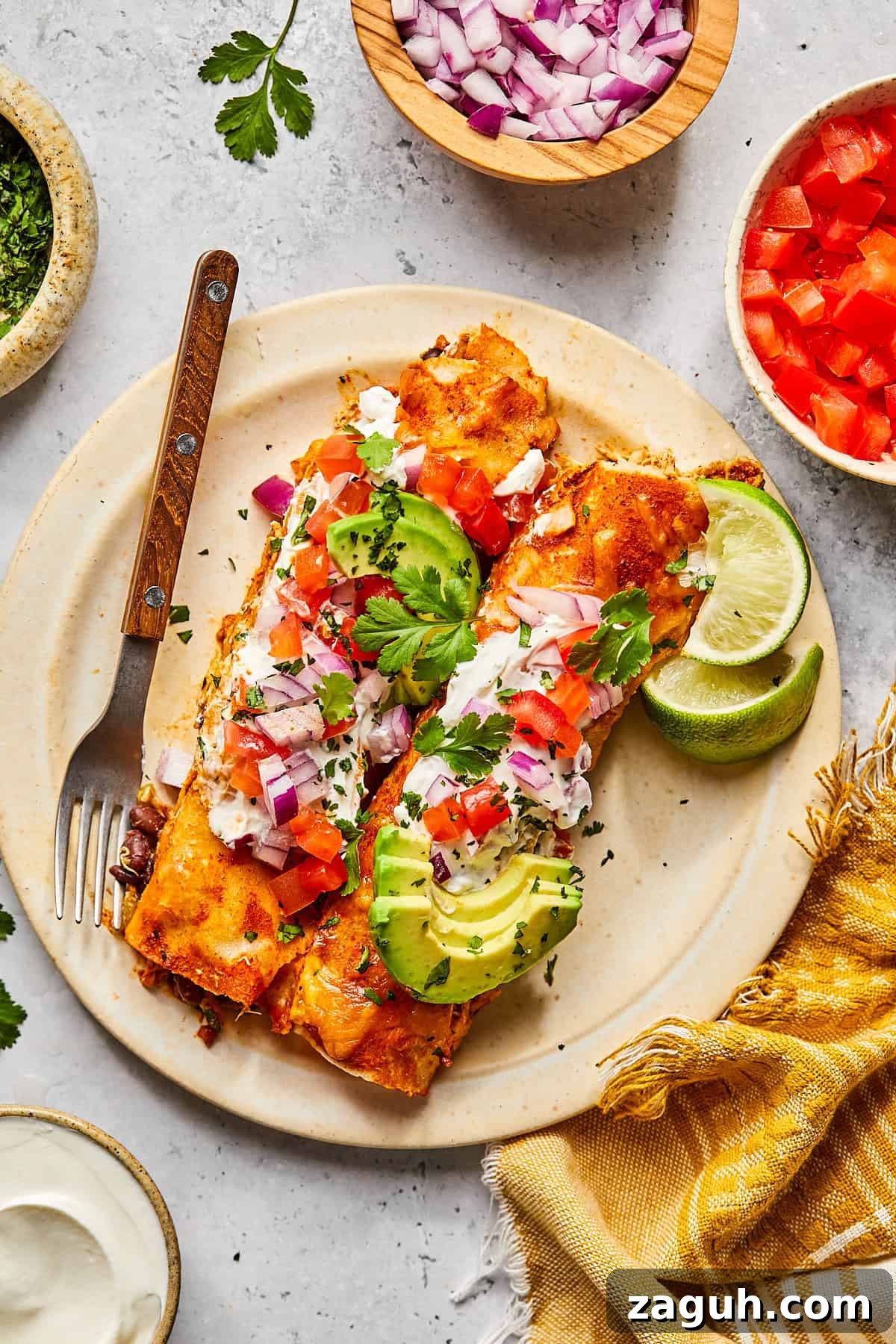 two enchiladas served on a white plate topped with salsa and avocado
