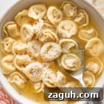Tortellini in Rich Bone Broth Recipe: Comforting Italian Soup 5 Shallow bowl full of tortellini simmered in bone broth and garnished with fresh cracked black pepper and grated Parmesan cheese.