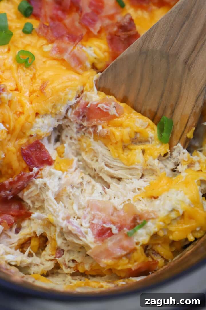 Creamy Slow Cooker Crack Chicken Recipe for Sandwiches & Dips 5 scooping out the crack chicken with a wooden spoon.