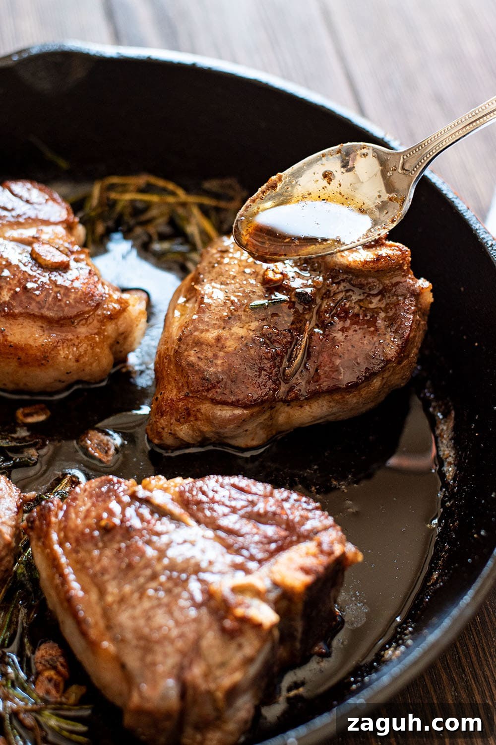 Cognac Butter Lamb Loin Chops Recipe for Elegant Dinner 4 A spoon pouring the pan drippings of cognac butter over perfectly seared lamb loin chops in a skillet.