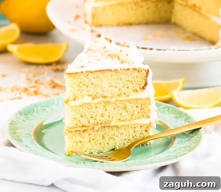 Moist Lemon Coconut Cake with Zesty Glaze 2 slice of coconut lemon cake on a plate with the cake on a cake stand behind it