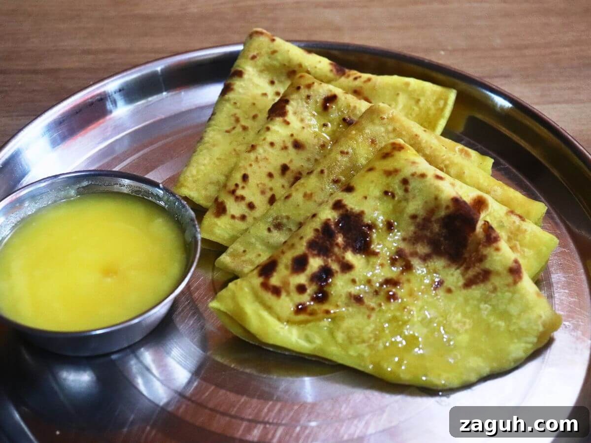 Authentic Maharashtrian Puran Poli Recipe (Puranachi Poli) 2 close-up of 4 maharashtrian puran poli served in a plate with a small bowl of ghee on side.