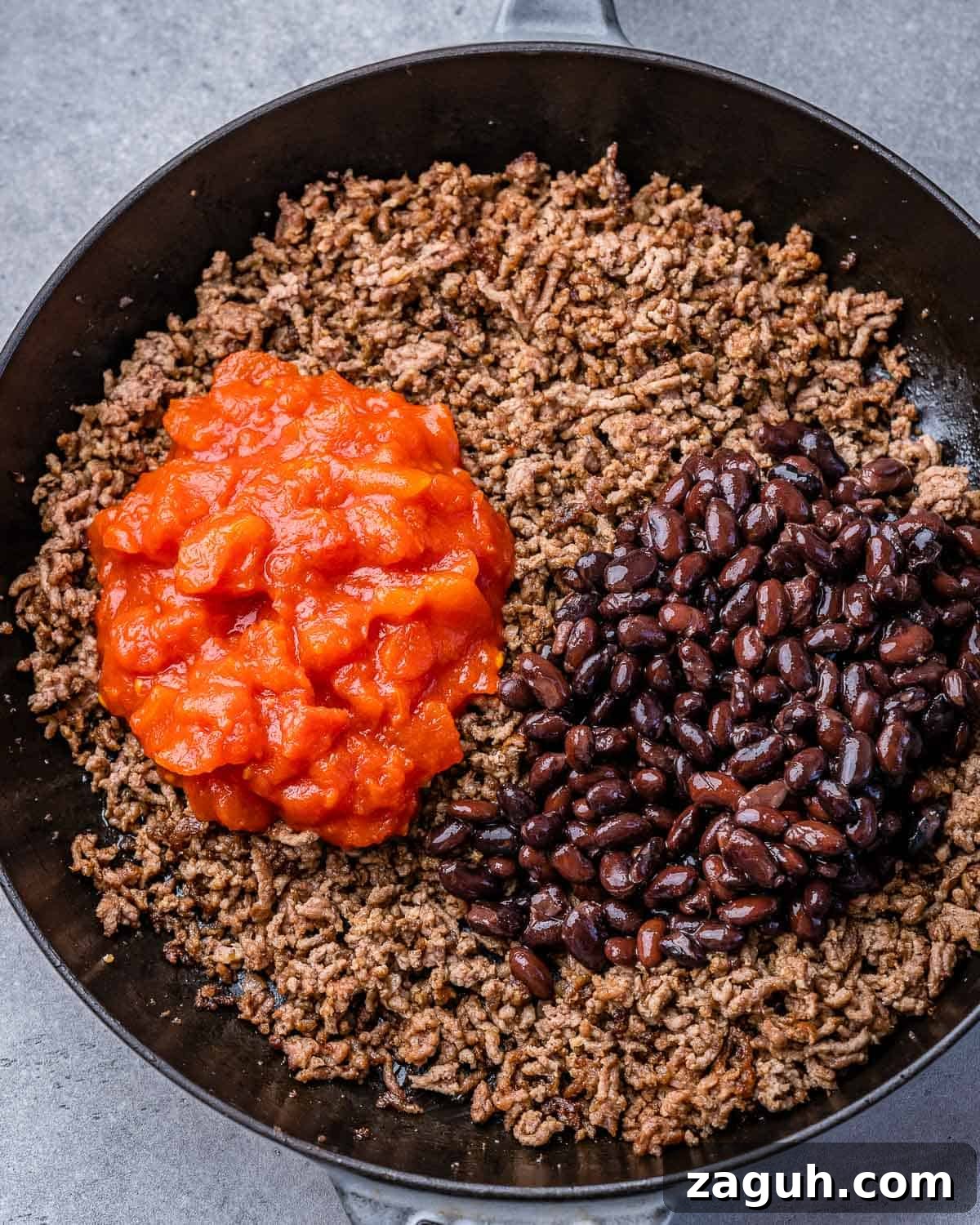 Spicy Chili Cheese Dip Recipe for Parties and Game Day 6 Adding tomatoes and black beans to browned beef.