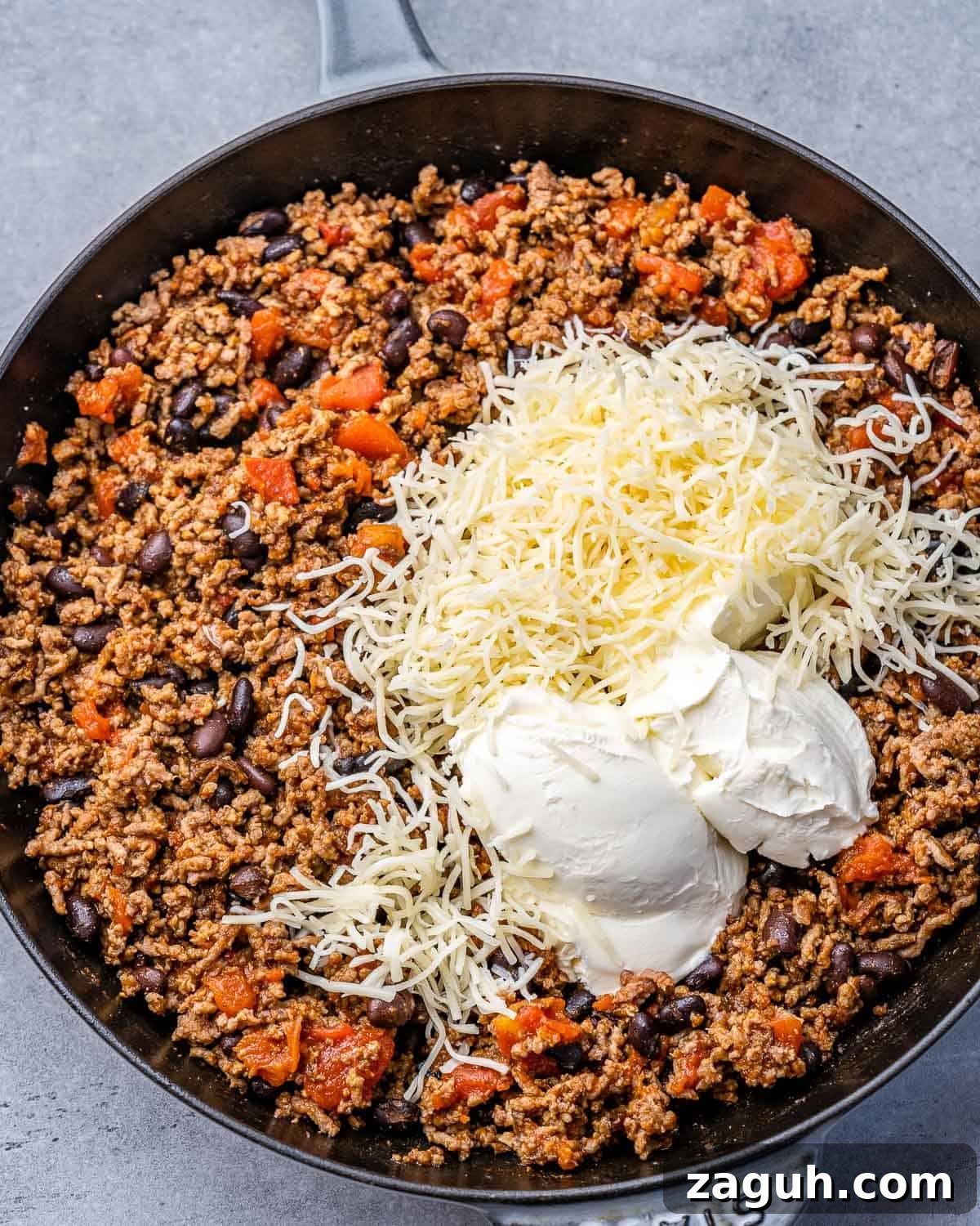 Spicy Chili Cheese Dip Recipe for Parties and Game Day 7 Adding cheese to beef in a skillet.