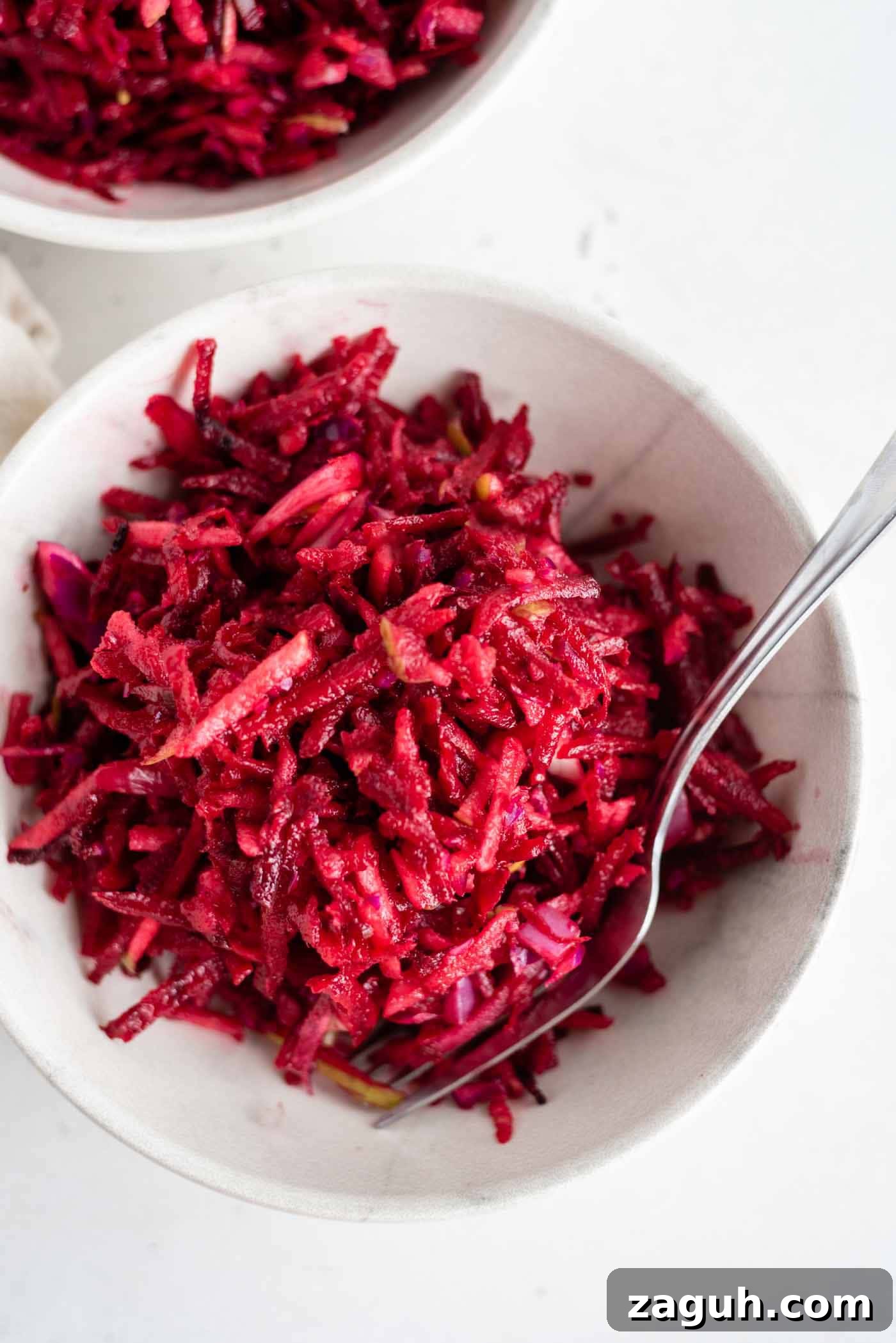 Crisp Apple and Beet Slaw Recipe for Fresh, Tangy Sides 2 Overhead shot of a beet, apple and cabbage slaw in a bowl with a fork.