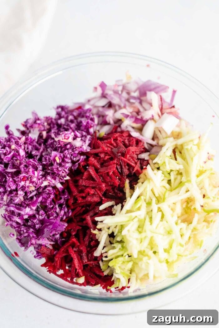 Crisp Apple and Beet Slaw Recipe for Fresh, Tangy Sides 4 Shredded cabbage, beet, apple and red onion in a mixing bowl.