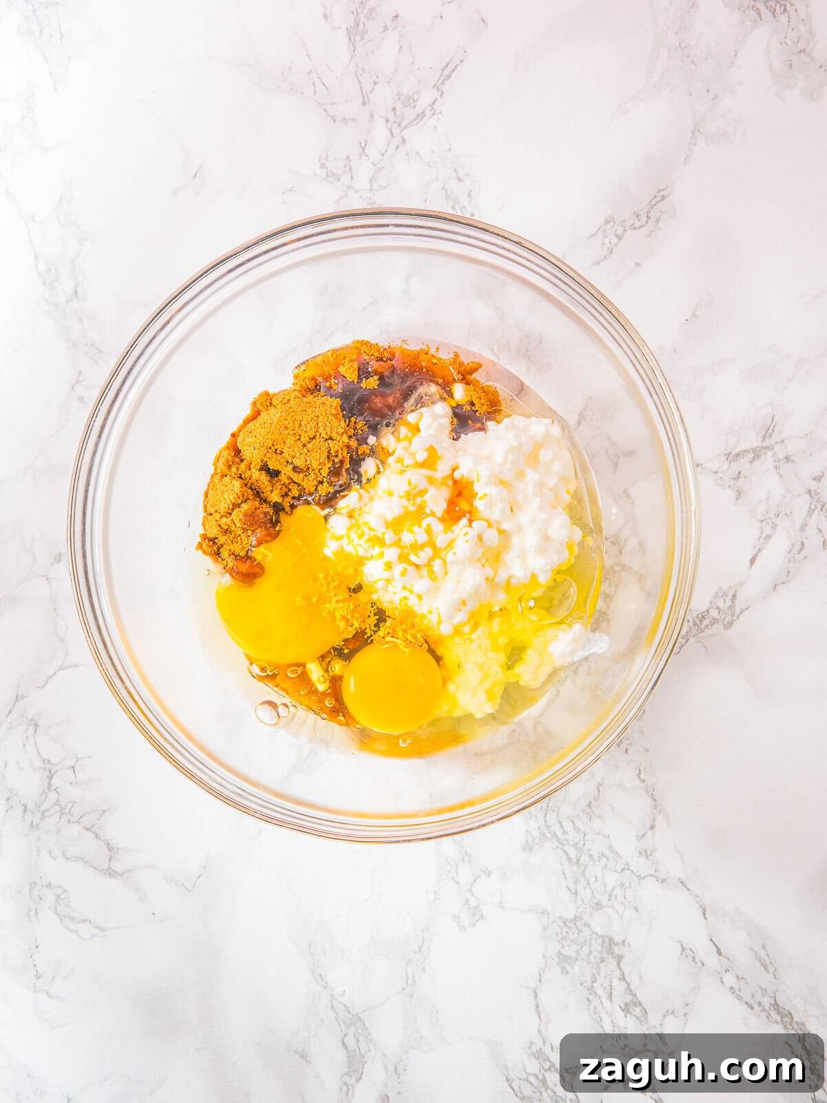 Cottage cheese, eggs, honey, and oil mixed in a bowl for Cottage Cheese Blueberry Muffins.