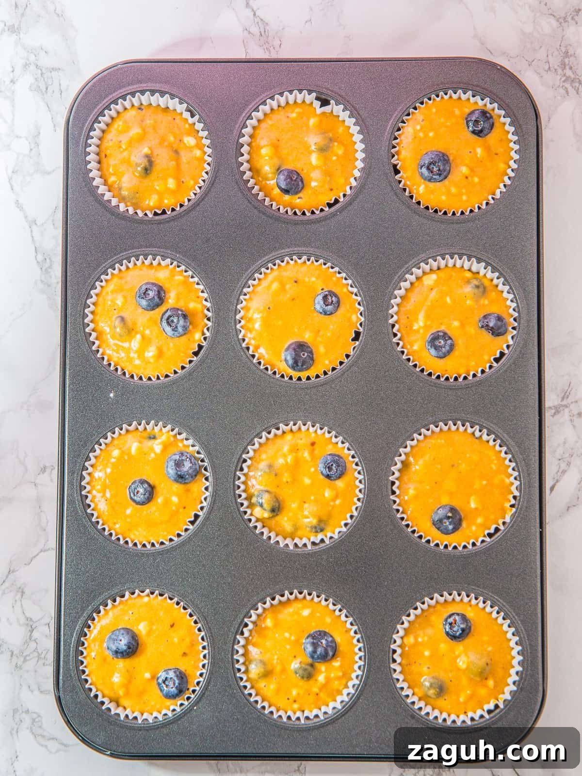 Muffin batter portioned into a lined muffin tin for Cottage Cheese Blueberry Muffins.