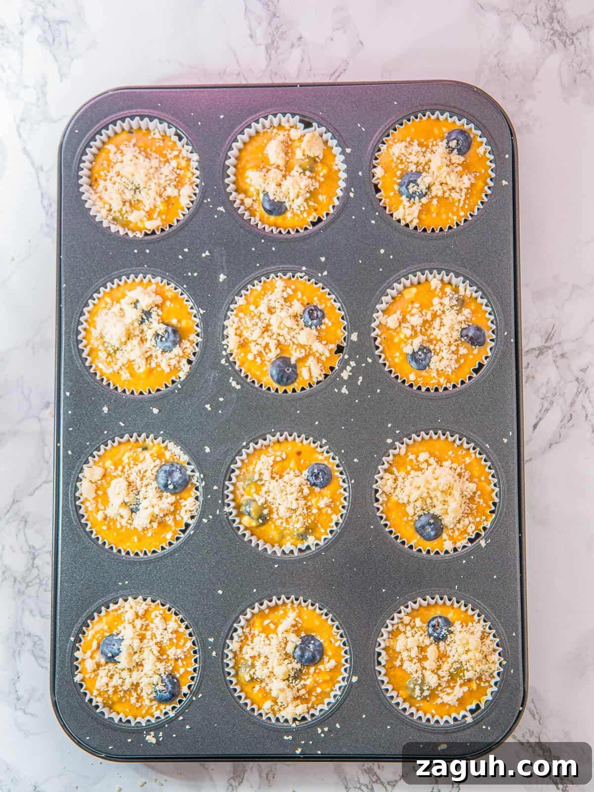Streusel topping sprinkled over the muffins for Cottage Cheese Blueberry Muffins.