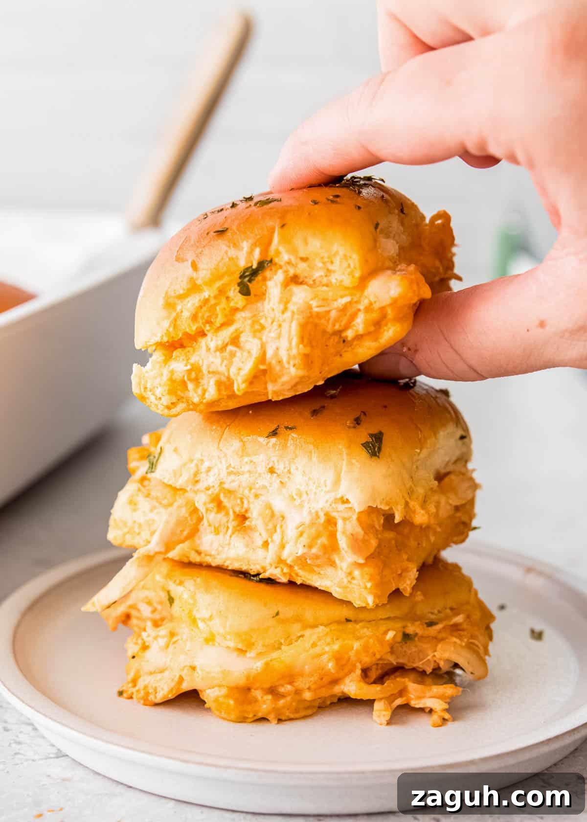Spicy Buffalo Chicken Sliders with Blue Cheese Slaw 14 a stack of three buffalo chicken sliders on a white plate