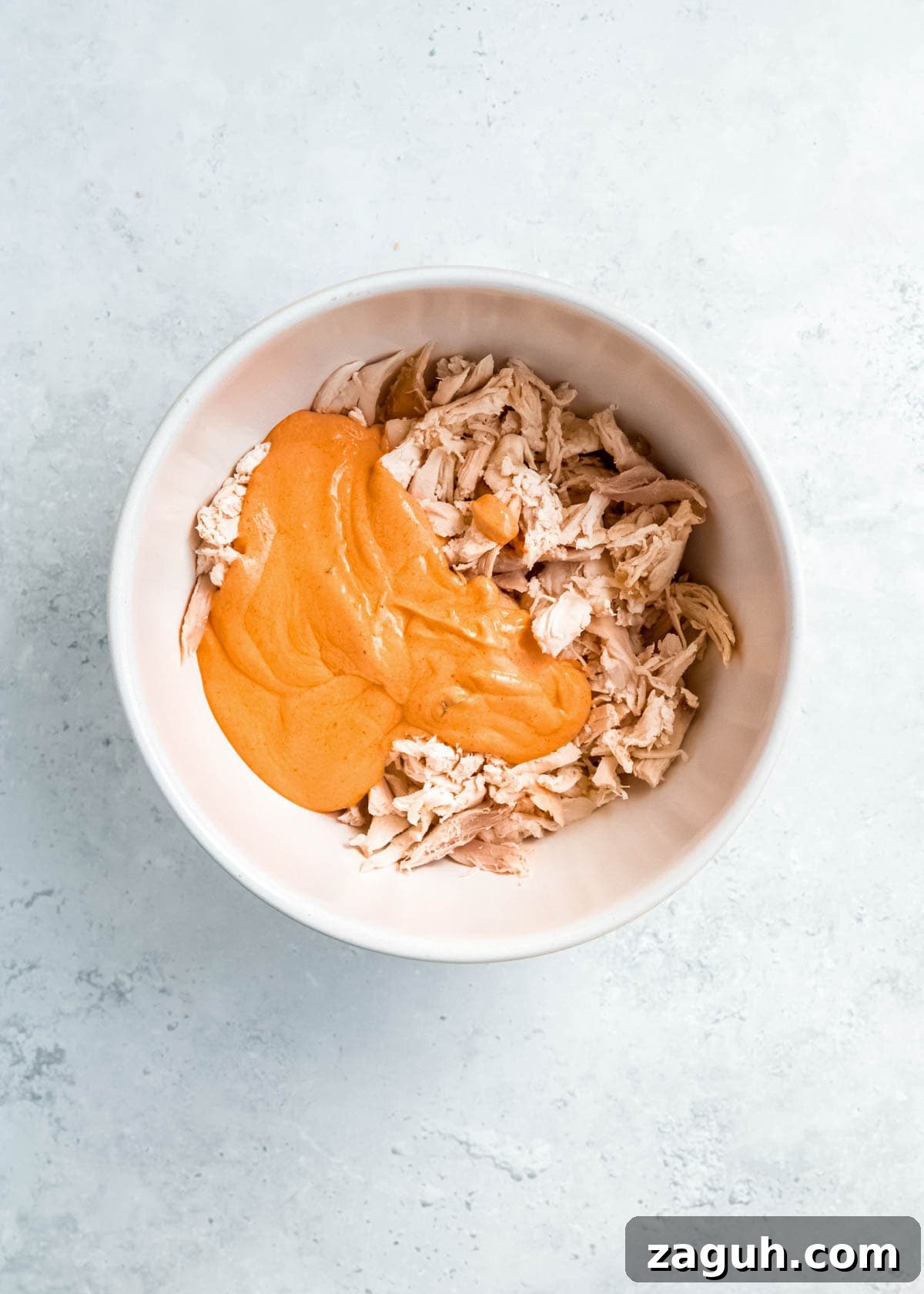 Spicy Buffalo Chicken Sliders with Blue Cheese Slaw 5 creamy buffalo sauce and shredded chicken in a white bowl