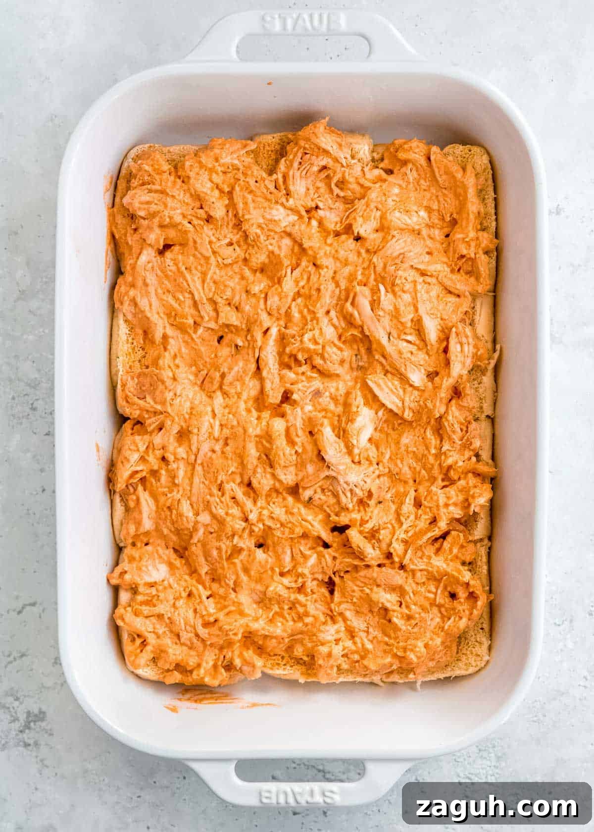 Spicy Buffalo Chicken Sliders with Blue Cheese Slaw 9 creamy buffalo chicken spread over the bottom buns in a white casserole dish