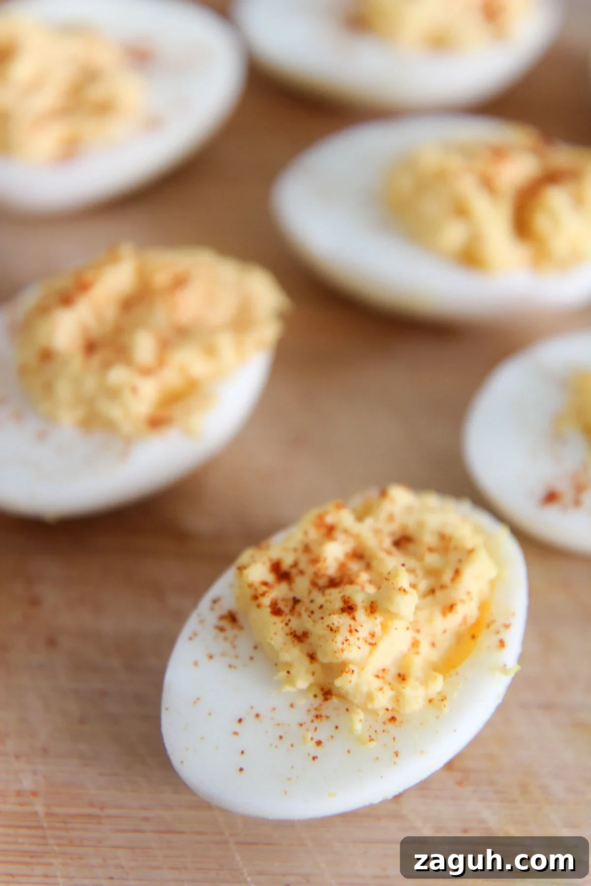 Perfect Classic Deviled Eggs Recipe for Parties and Holidays 2 deviled eggs with paprika on a wooden board