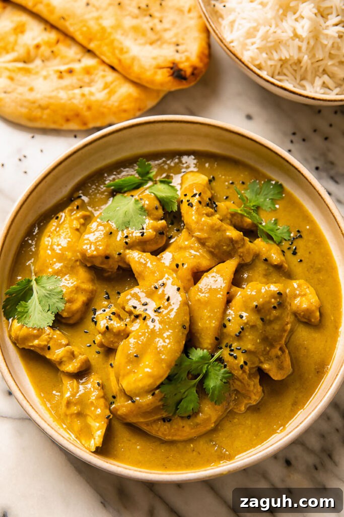 Top down shot of rich chicken and mango curry in a bowl topped with fresh cilantro