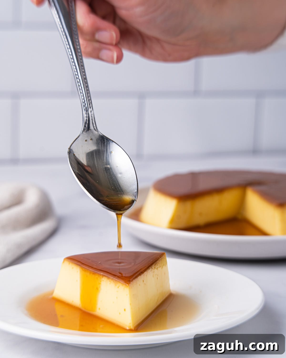 Creamy Vietnamese Bánh Flan Recipe — Classic Caramel Custard 9 Slice of flan on a plate with spoon drizzling caramel on top.