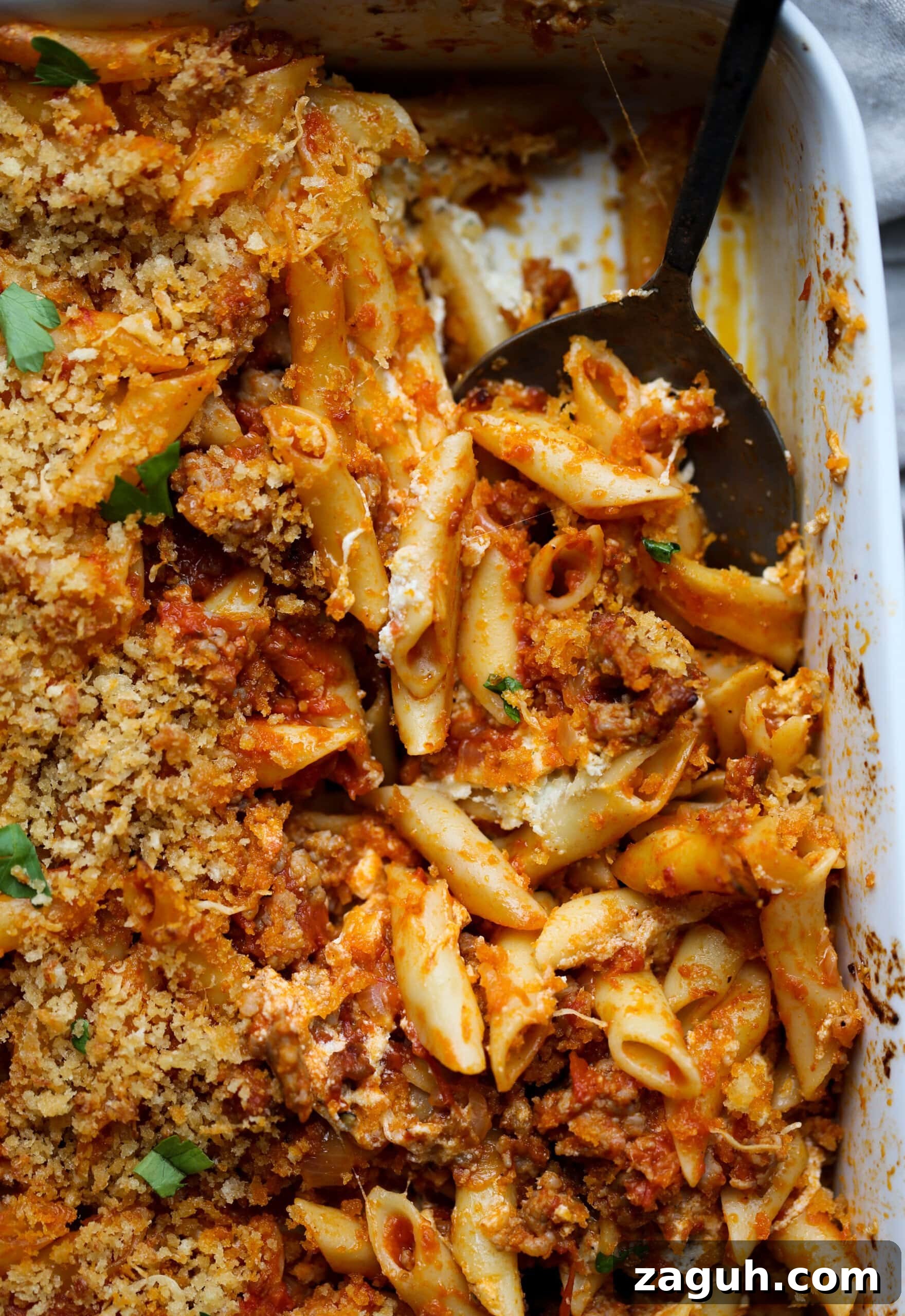 Creamy Baked Mostaccioli with Melted Cheese 14 Baked mostaccioli pasta is scooped from a casserole dish.