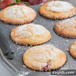 Fresh Strawberry Sourdough Muffins Recipe for Soft, Tangy Loaves 2 Muffins in a tin, topped with sugar, with a red and white checkered cloth and fresh strawberries nearby.