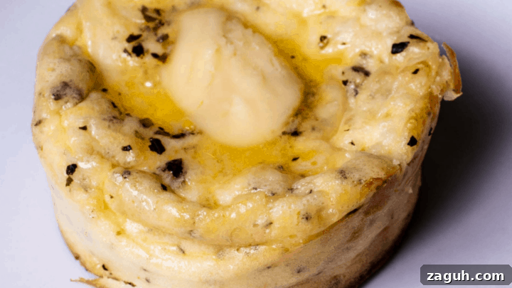 single cream cheese muffin with pat of butter on white plate