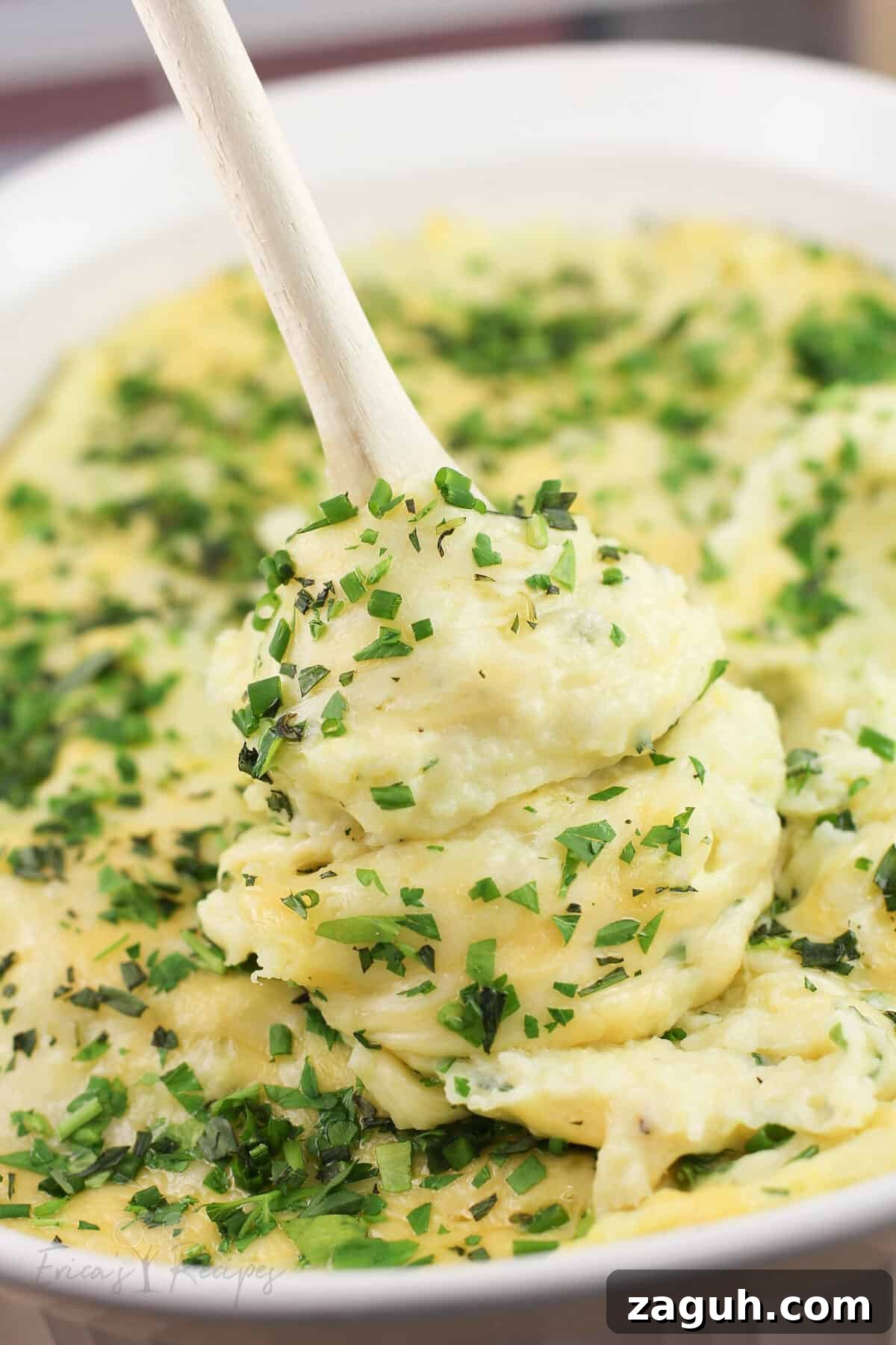 Creamy Gruyère, Garlic & Gouda Mashed Potatoes Recipe 12 wood spoon lifting up cheesy mashed potatoes from bake dish