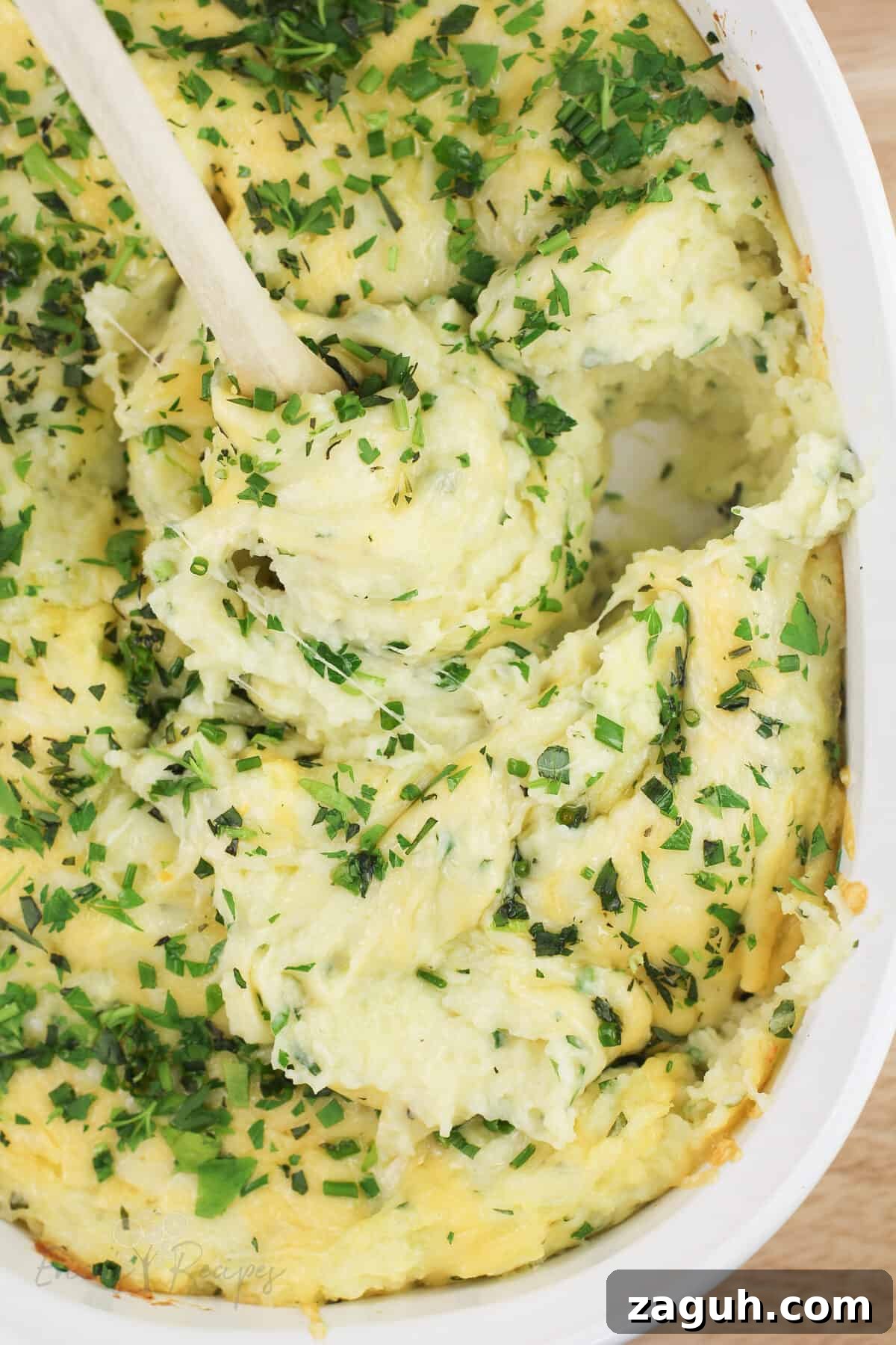 Creamy Gruyère, Garlic & Gouda Mashed Potatoes Recipe 13 spoon stirring prepared recipe topped with French fine herbs