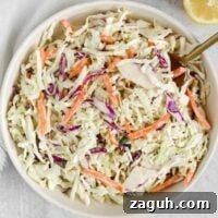 Creamy Paleo & Whole30 Coleslaw Recipe for Simple Sides 13 Creamy coleslaw in a serving bowl with a gold spoon.