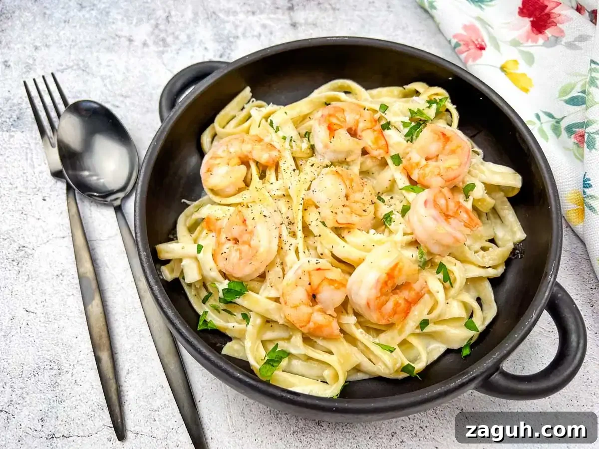 31 Bold Seafood Recipes for Big Flavor with Simple Ingredients 11 A bowl of olive garden creamy shrimp alfredo pasta served in a black bowl with a spoon.