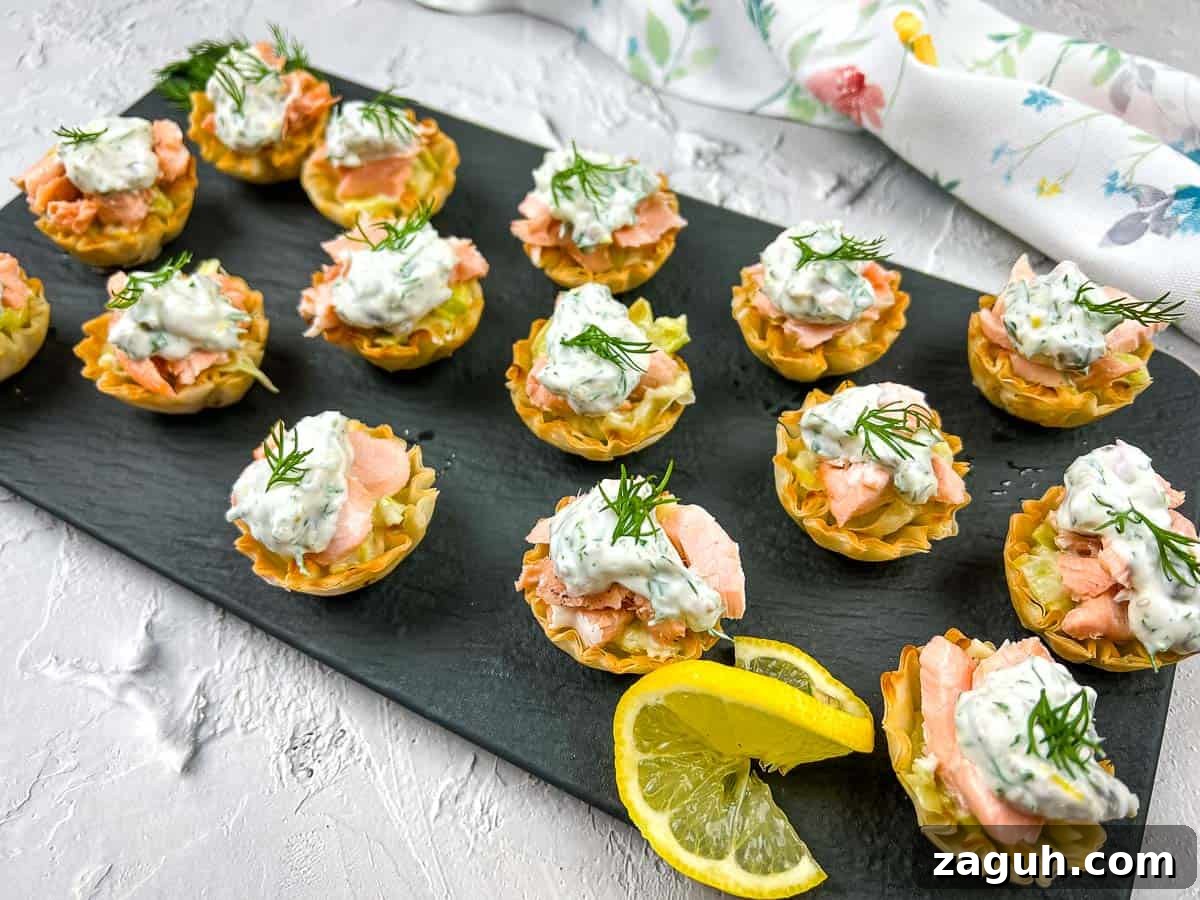31 Bold Seafood Recipes for Big Flavor with Simple Ingredients 27 Salmon & Leek Phyllo Tartlets with lemon wedges on a black plate.