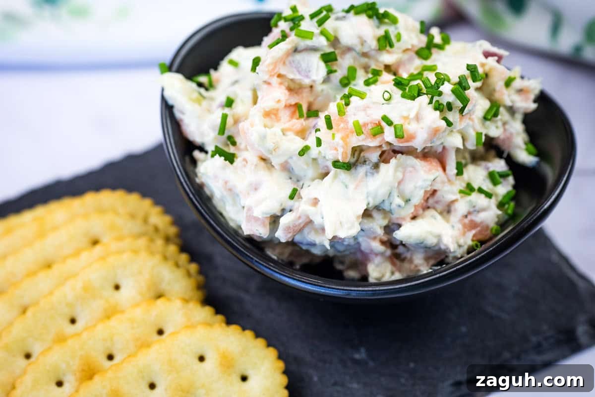 31 Bold Seafood Recipes for Big Flavor with Simple Ingredients 7 Bowl of smoked salmon spread garnished with chopped chives next to crackers on a slate platter.