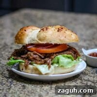 slow cooker barbecued beef shown in a toasted bun with lettuce and tomatoes