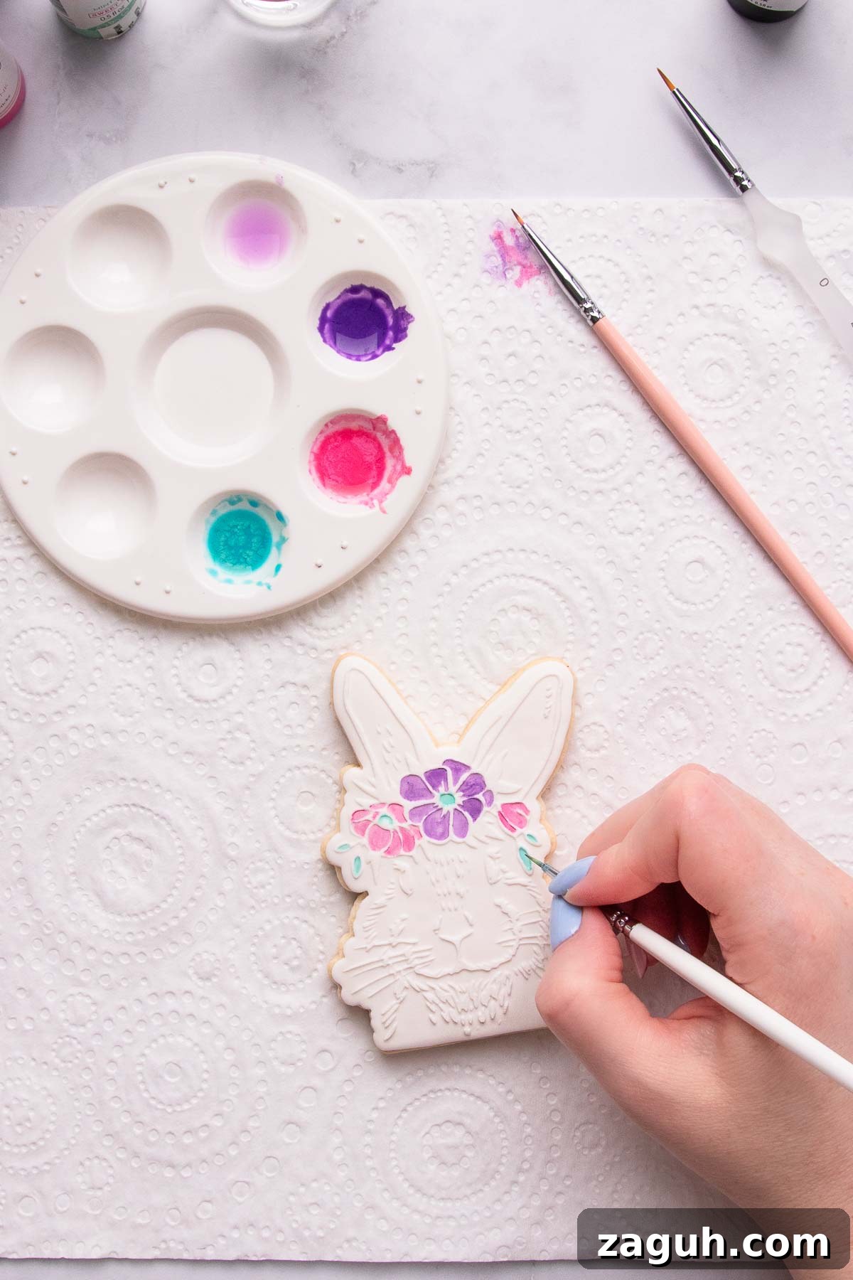 Stamped Fondant Cookies: Step-by-Step Guide for Beautiful Designs 13 A hand painting the floral crown on a bunny head cookie using edible paint.