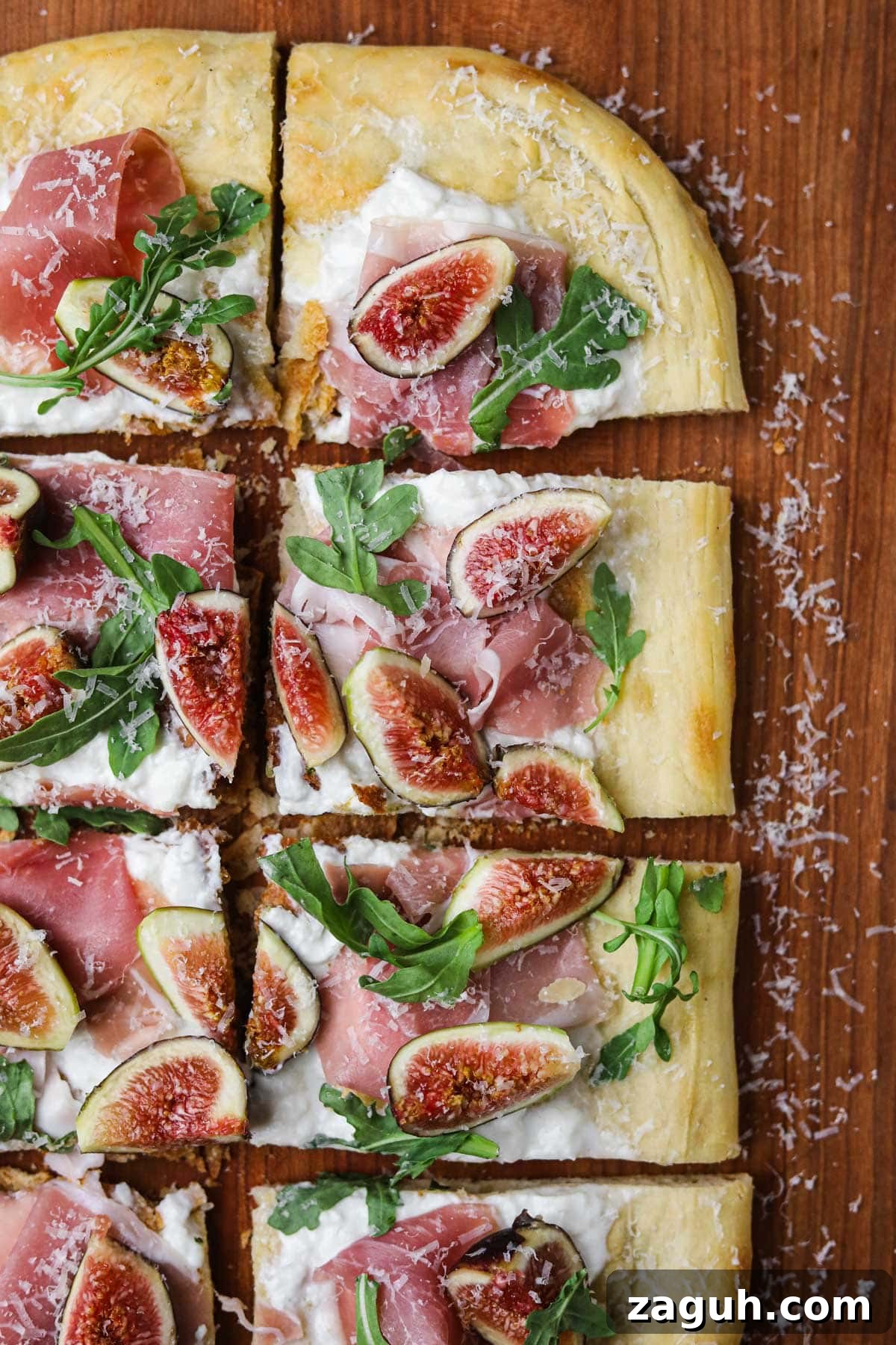 Fig, Burrata & Prosciutto Pizza with Honey and Arugula 2 White pizza with fig, prosciutto, arugula, and burrata on a wooden serving board.