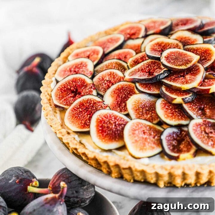 Fig tart with whipped mascarpone and honey filling on a marble serving platter.
